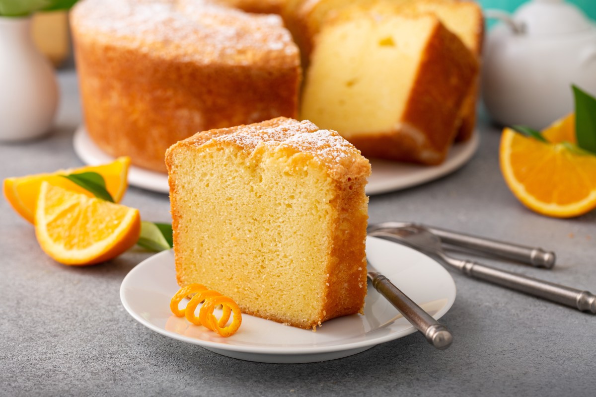 Torta de naranja dorada con costra crujiente de azúcar y ralladura fresca sobre mesa rústica