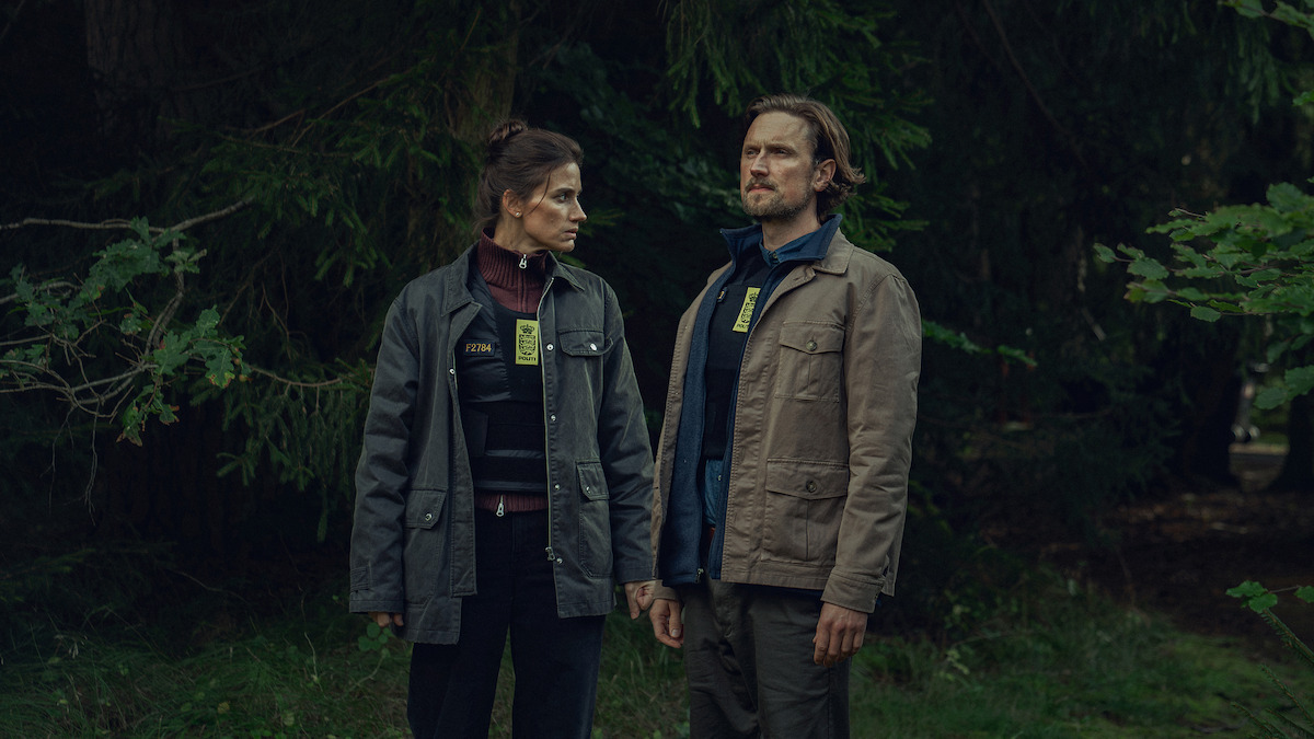 Detectives Thulin y Hess analizando pistas en una escena oscura de 'The Chestnut Man' temporada 2 con símbolos inquietantes