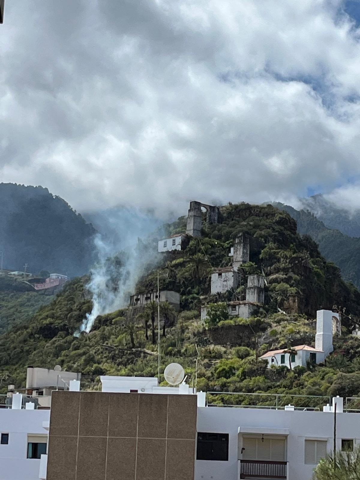 Brigadas forestales combaten el incendio en Los Molinos de Bellido con humo denso y vegetación ardiente al fondo del Parque Natural de Cumbre Vieja