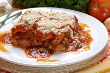 Lasaña de huevo y atún en capas con queso mozzarella derretido y salsa marinara, lista para hornear