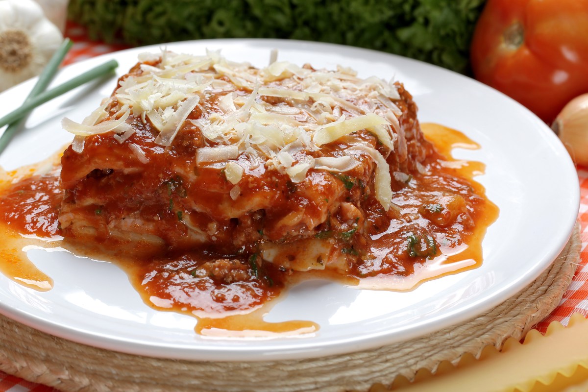 Lasaña de huevo y atún en capas con queso mozzarella derretido y salsa marinara, lista para hornear