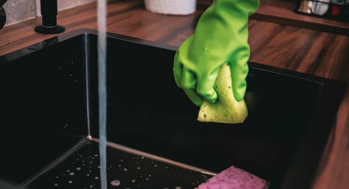 Primer plano de una bandeja de escurridor con restos orgánicos y gotas de agua estancada, foco invisible de bacterias como E. coli en la cocina