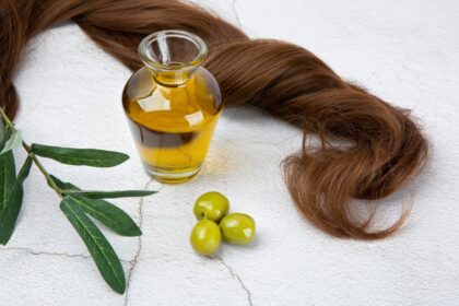 Frasco de aceite de oliva virgen extra junto a un cepillo con hebras de cabello saludable, destacando su uso contra la alopecia