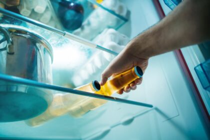 Botellas de cerveza oscuras en refrigerador con luz tenue para conservar sabor