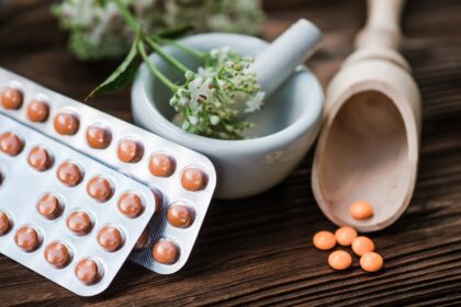Selección de hierbas medicinales como pasiflora, lavanda y valeriana en mesa de madera con frascos de extractos