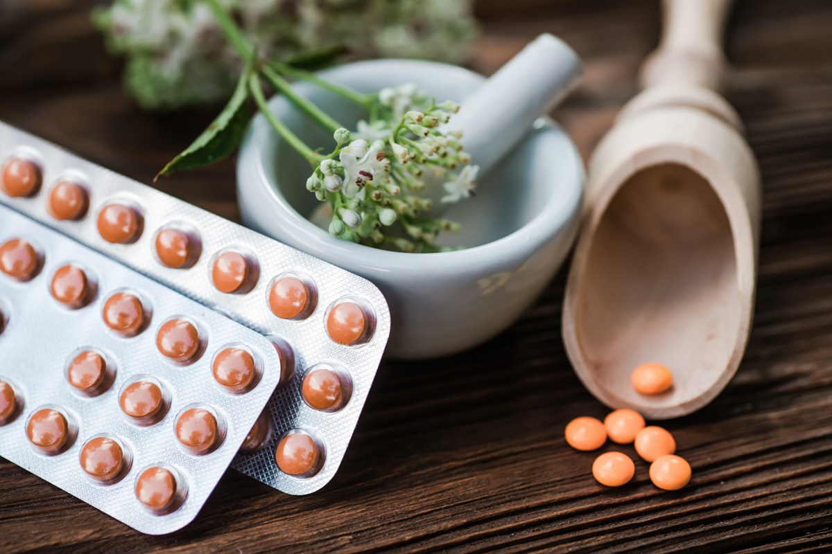 Selección de hierbas medicinales como pasiflora, lavanda y valeriana en mesa de madera con frascos de extractos