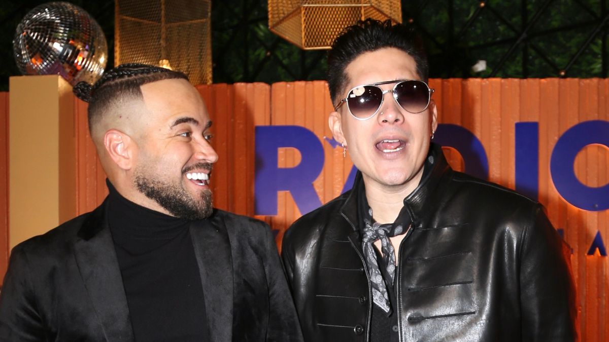 Chyno y Nacho en escenario anunciando el Radio Venezuela World Tour 2026-2027 con banderas de Latinoamérica