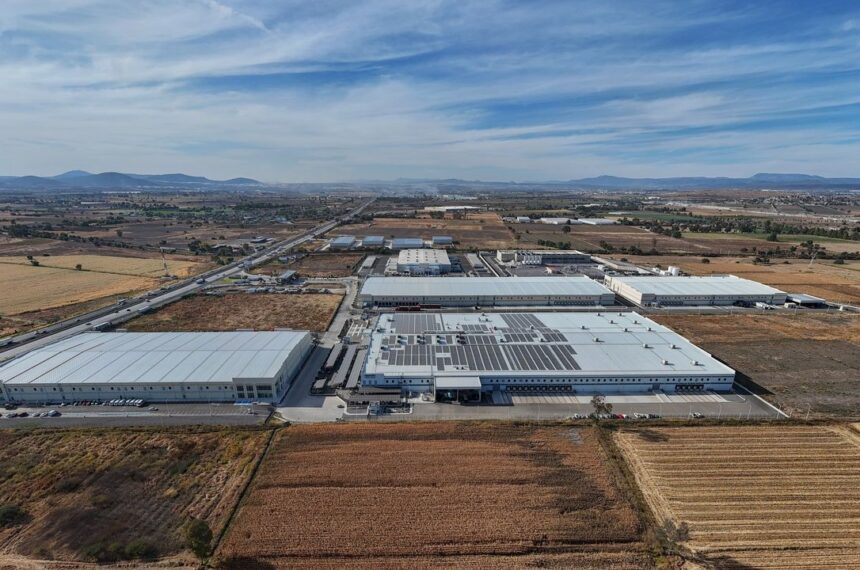 Parque industrial en Querétaro con imponentes centros de datos de AWS y Microsoft, rodeados de tierras agrícolas en contraste con la infraestructura tecnológica
