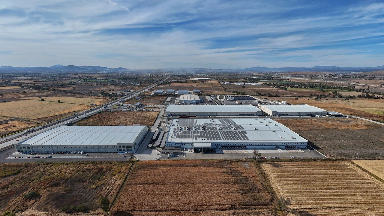 Parque industrial en Querétaro con imponentes centros de datos de AWS y Microsoft, rodeados de tierras agrícolas en contraste con la infraestructura tecnológica