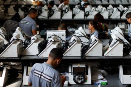 Técnico del TSE revisa una urna electrónica brasileña con pantalla táctil y lector de huellas, símbolo de 30 años sin fraudes comprobados