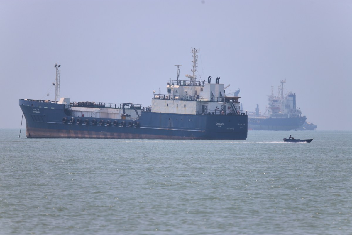 Barcos comerciales transitando el estrecho de Ormuz con bandera de Irán al fondo