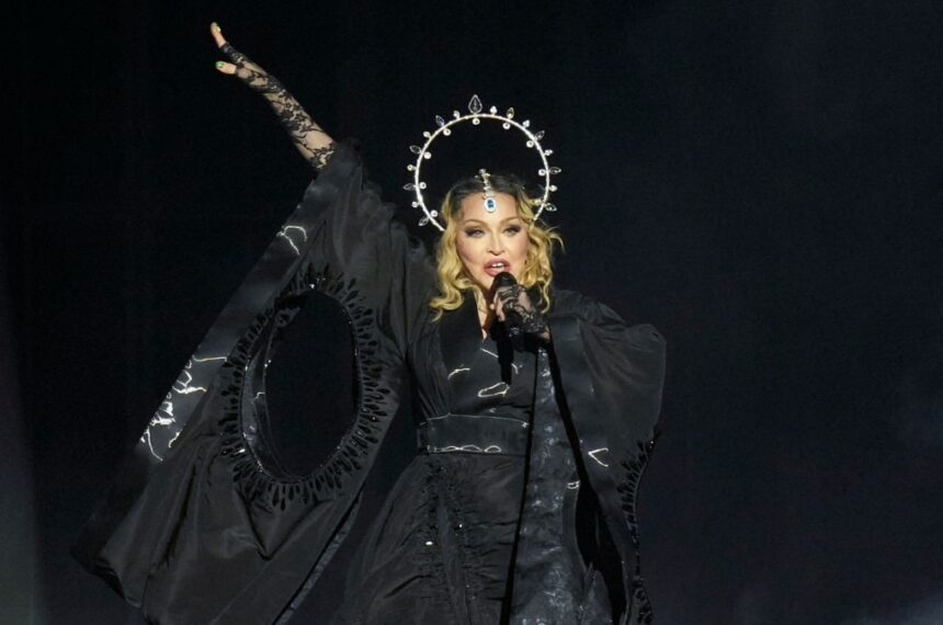Madonna en pleno concierto sorpresa en Times Square 2024, rodeada de fans bajo las pantallas gigantes con luces neón