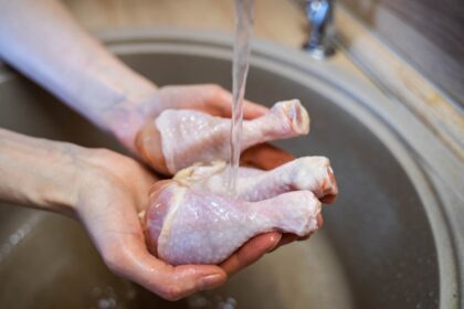 Pollo crudo en tabla de cortar con cuchillo y bacterias invisibles
